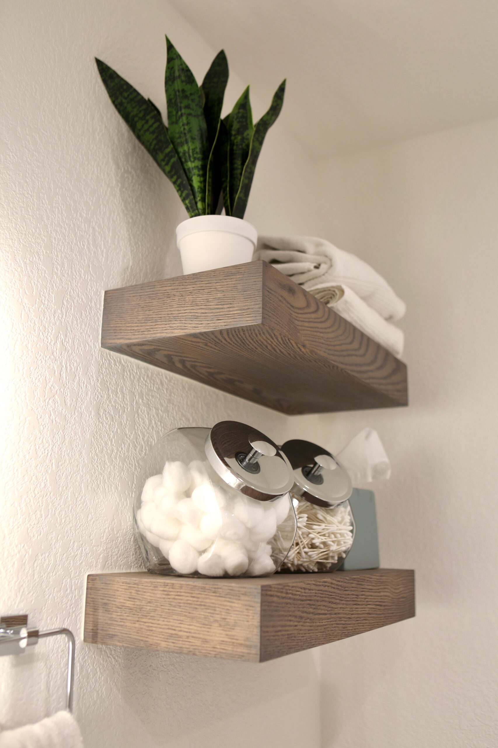 Decorative wooden bathroom shelves with towels and potted plant